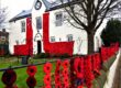 A white building decorated with large red poppy displays and a soldier silhouette.